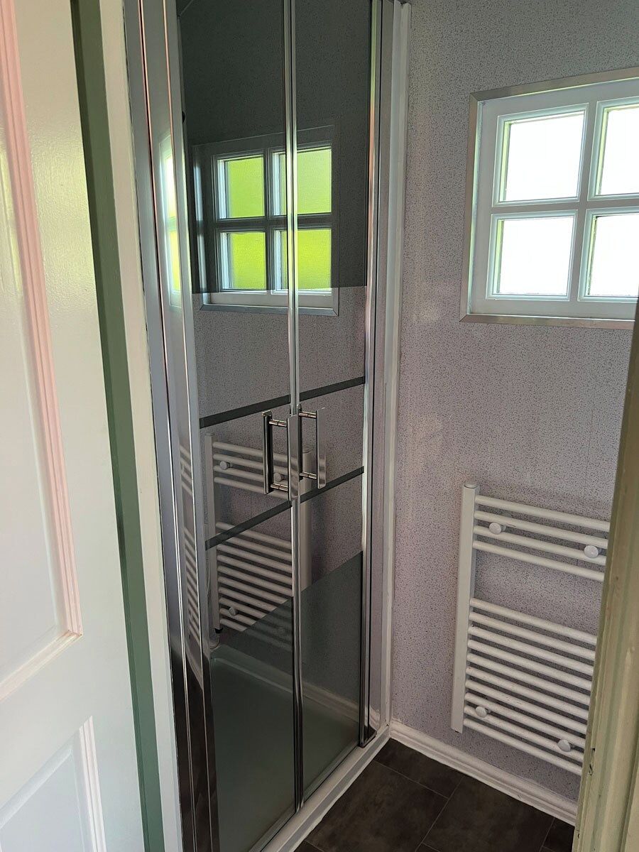 A room with a glass door leading to a balcony, a radiator, and a window.