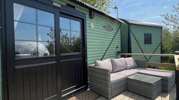 A wooden deck with a wicker sofa and a small table, a black door labeled 'PRIVATE,' and a green building with the name 'PULMAN' on the side.