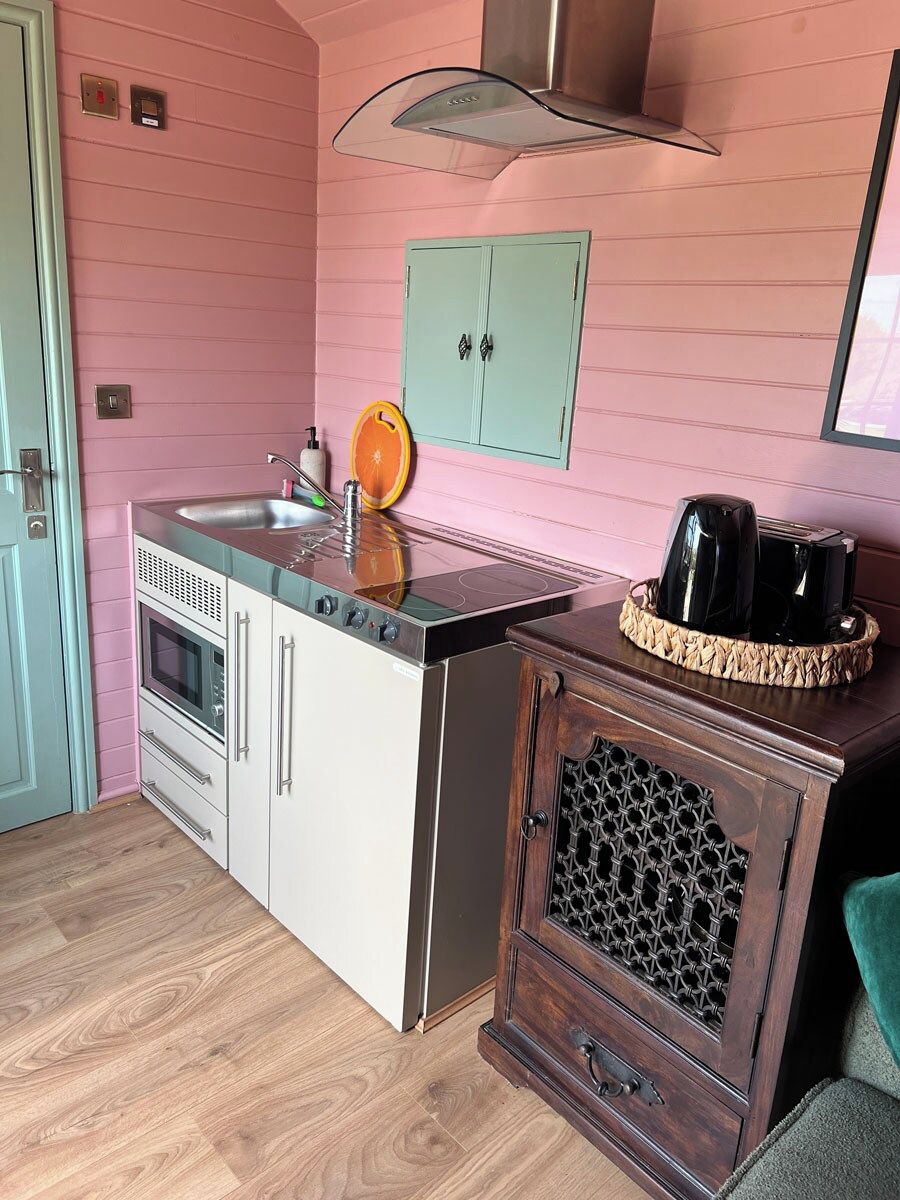 A compact kitchen with a sink, stove, and wooden cabinets.