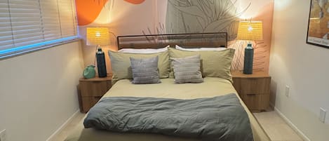 A bedroom with a bed, two bedside tables, a ceiling fan, and wall art.