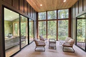 Un intérieur moderne avec de grandes fenêtres, des meubles en osier et un plafond en bois.