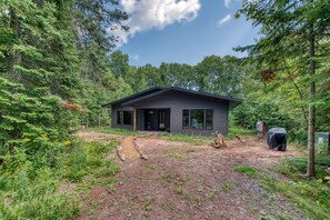 Une cabane dotée d’un porche, entourée d’une forêt dense.