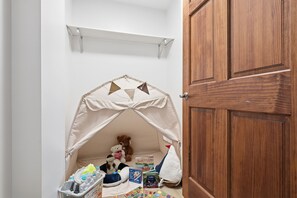 Zona de jocs per a infants amb una tenda, joguines i llibres.