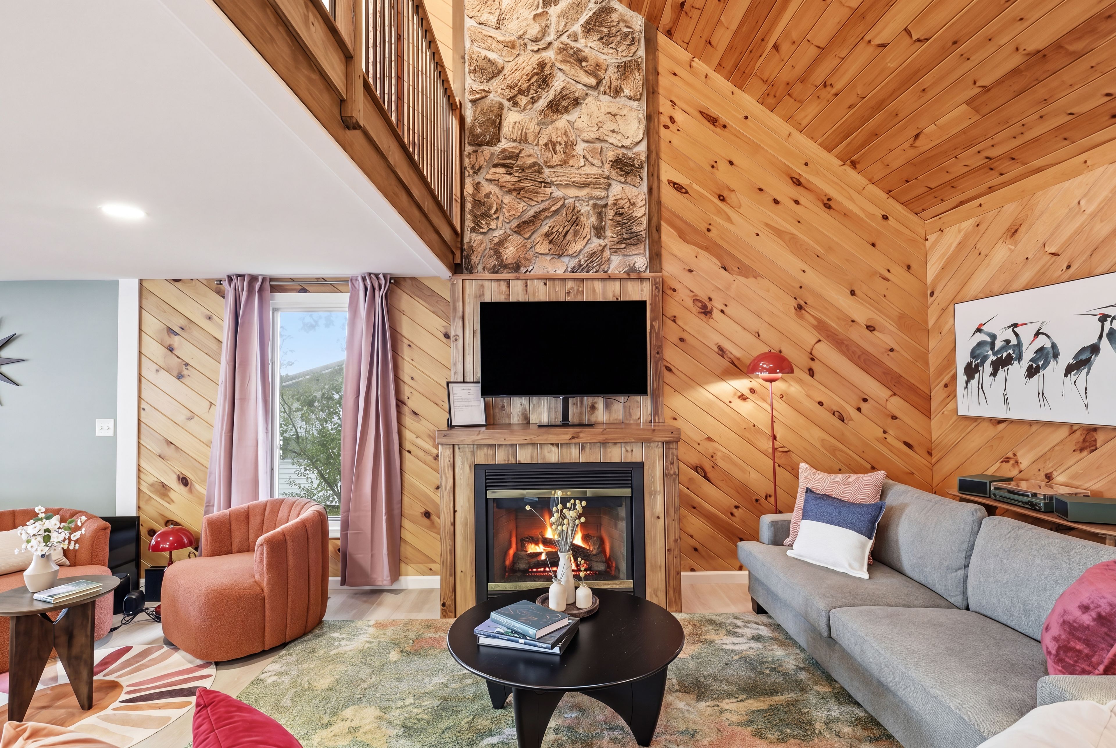 Ein modernes Wohnzimmer mit Kamin, Holzwänden, einer Couch, einem Fernseher und einer Treppe.
