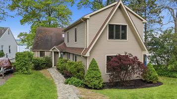 A two-story house with a stone pathway leading to the front door, surrounded by well-maintained landscaping and trees.
