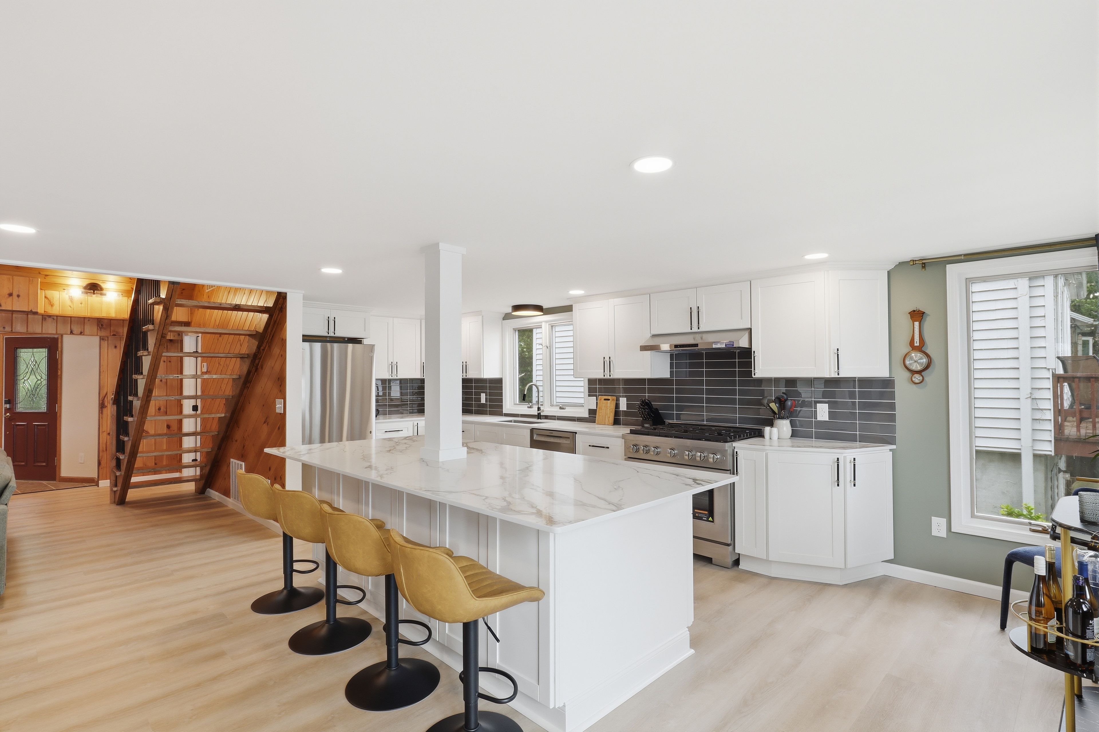 A modern kitchen with white cabinetry, a marble island, and a stainless steel stove.