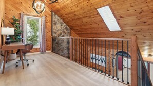 A wooden interior with a desk, chair, lamp, and a view of a stone wall. - The Vita and Vine: Lakefront, Outdoor Theater (Rushville)