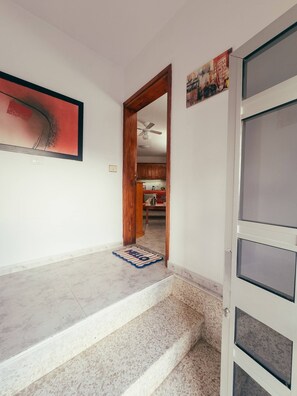 Ein Flur mit einer Treppe zu einem Zimmer, das einen Deckenventilator hat.