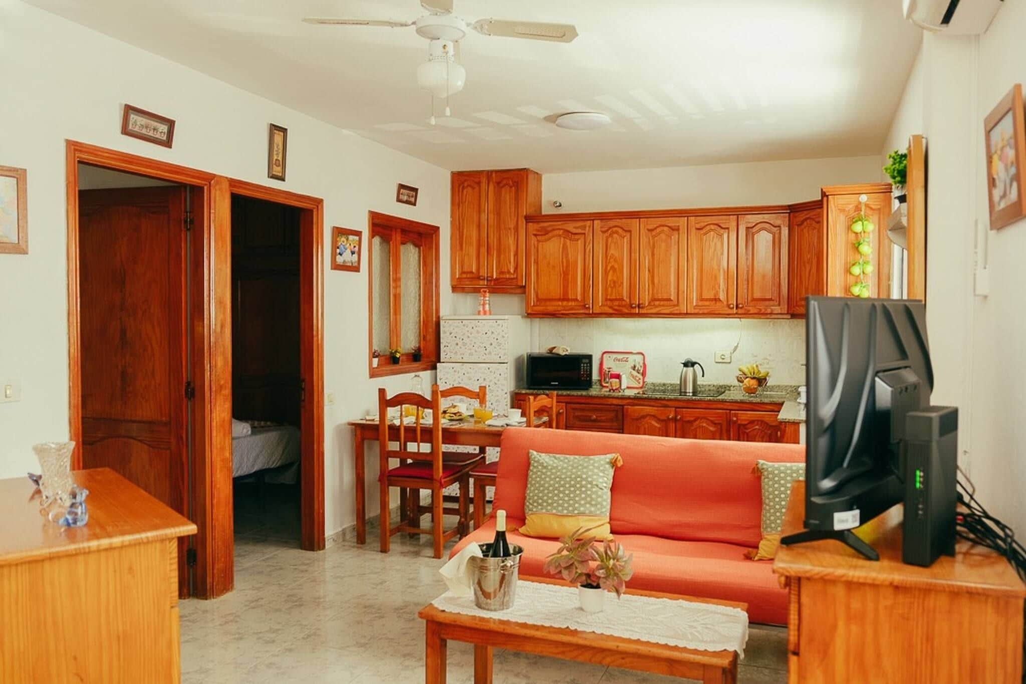 Een knus woongedeelte met een kitchenette, een eethoek en een zithoek met een bank en een televisie.