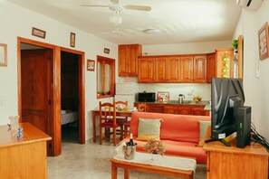 A compact living space with a kitchenette, a dining area, and a seating area with a sofa and a television. - Apartment 2 | Aldea Blanca | 2 bedrooms | Hiking trails (Aldea Blanca)