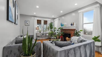 A living room with a fireplace, grey upholstered seating, and a large window.