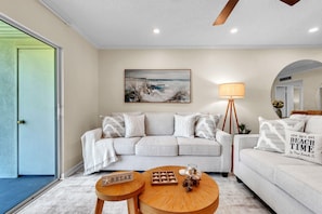 A living room with a sofa, a coffee table, a lamp, a painting, and a sign that says 'RELAX'. - Vista Verde East 105 (St. Petersburg)