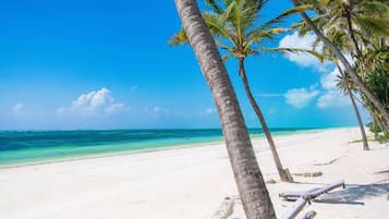 A beach with white sand and clear blue water.