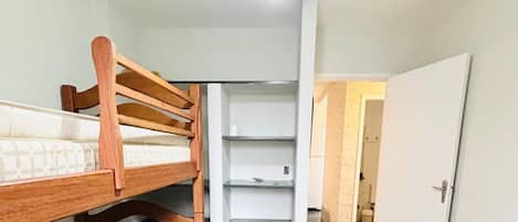 Una habitación con literas, ventilador de techo y una escalera que lleva a una puerta.