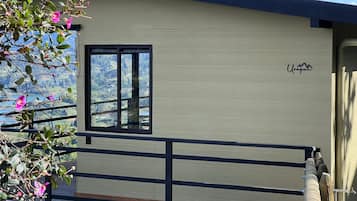 Un edificio moderno con terraza de madera, una ventana y vistas a un paisaje montañoso.