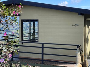 A modern building with a wooden deck, a window, and a view of a mountainous landscape. - Alto Sereno (El Peñol)