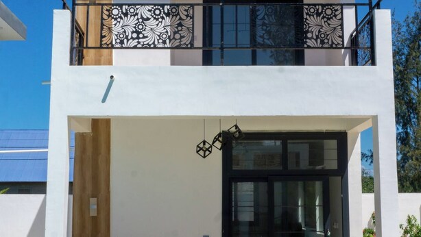 A modern two-story house with a balcony, a swimming pool, and a garden. - Kameleon Villa’s - Bungalow 3 (Kiwengwa)