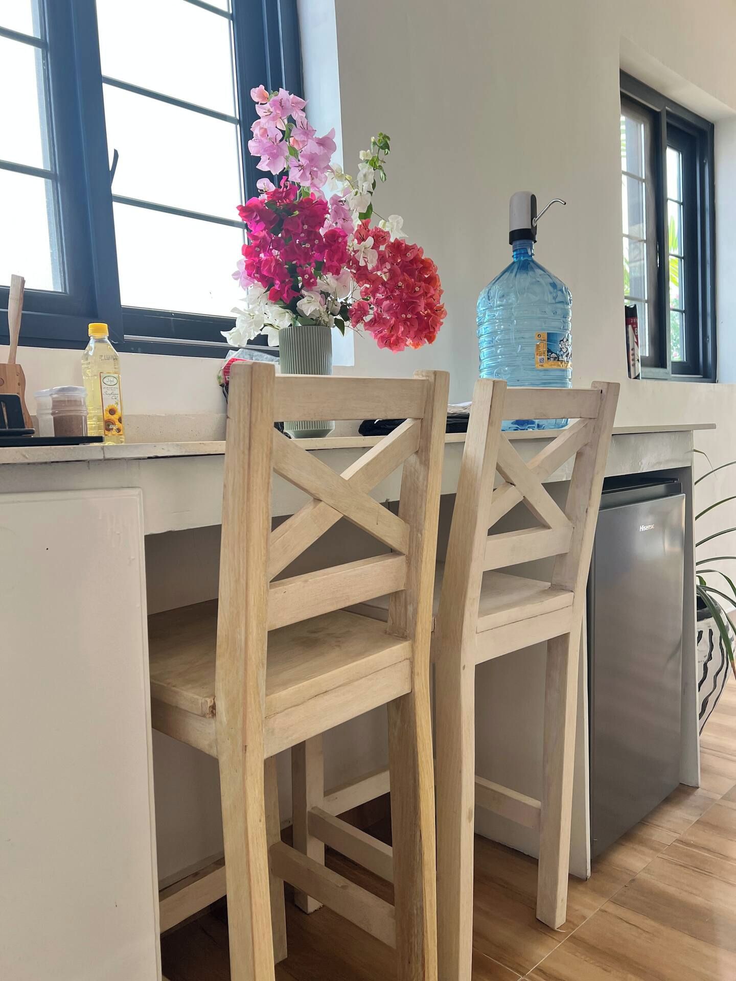 A kitchen with wooden chairs, a water dispenser, and a vase with flowers.
