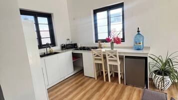 Une cuisine de taille réduite avec des meubles blancs, un coin repas comprenant une table et des chaises, un ventilateur de plafond et une fenêtre offrant une belle vue.