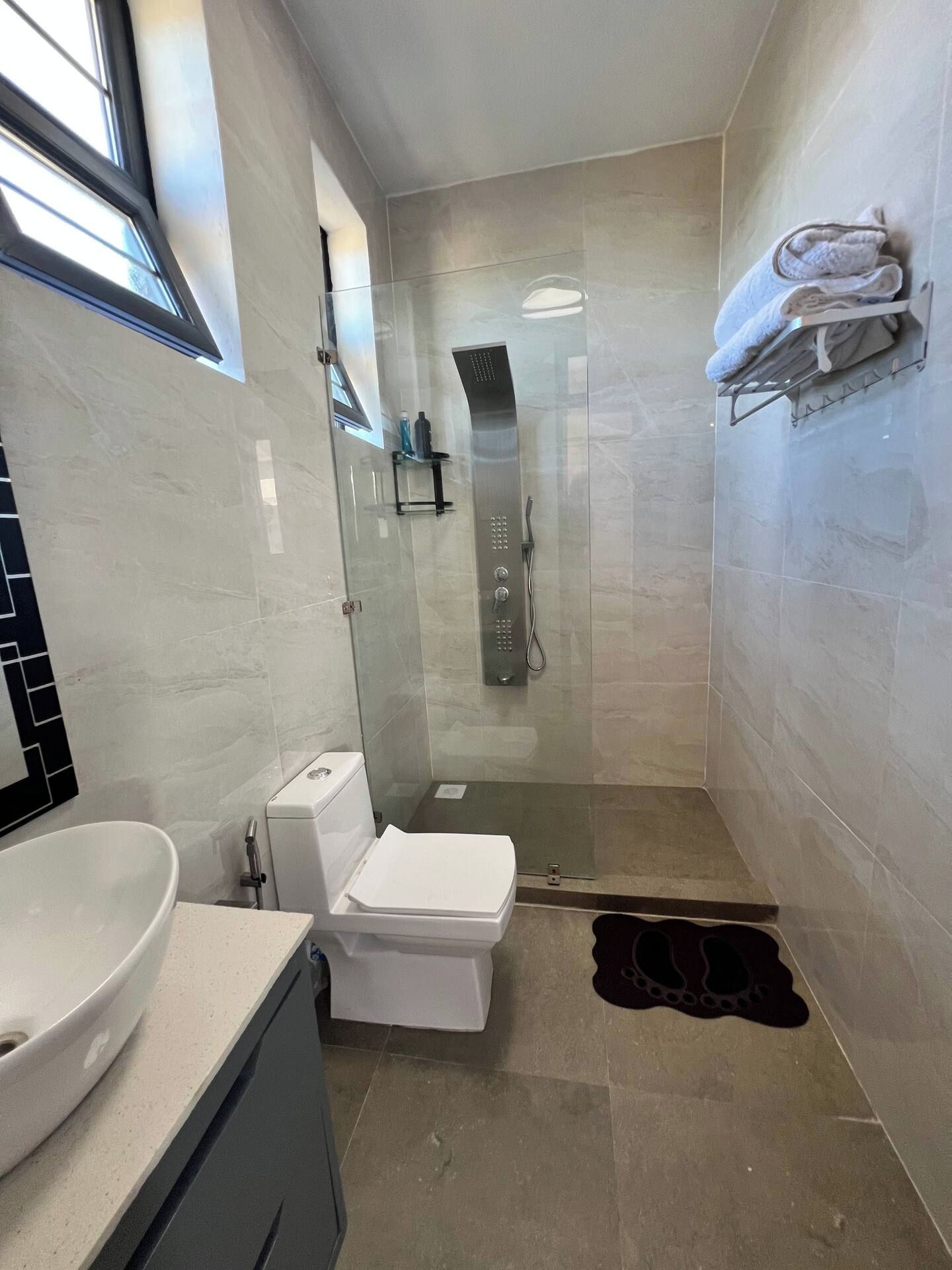 Un bagno moderno con doccia vetrata, un water e un lavandino.