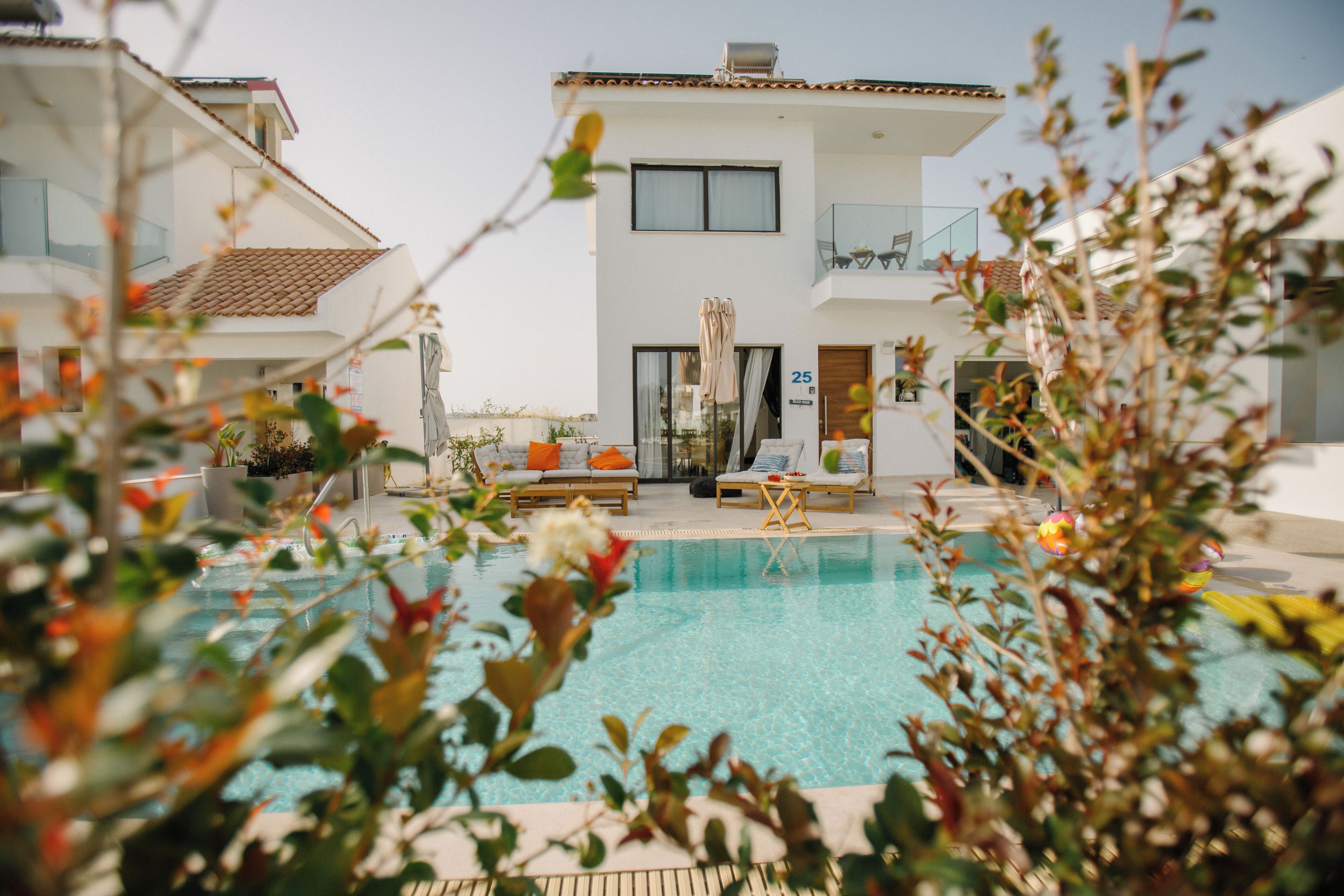 A modern hotel with a swimming pool, outdoor seating, and a clear view of the pool area.