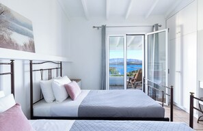 A bedroom with a bed, a balcony with a view, and a painting on the wall. - Evangelia, a tranquil Corfu retreat with panoramic sea views and easy village access (Kassiopi)