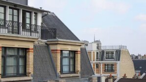 Un immeuble résidentiel à plusieurs niveaux, doté d’un balcon avec une rambarde en métal et d’une cheminée.