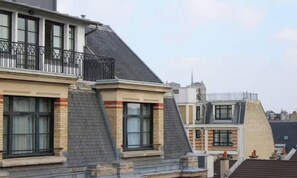 Ein Wohngebäude mit mehreren Dachgeschossen, einem Balkon mit Metallgeländer und einem Schornstein.