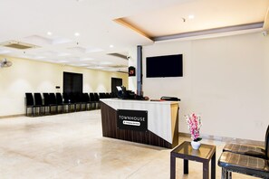 A reception area with a 'Townhouse' sign, a reception desk, a flat-screen TV, a row of chairs, and a potted plant.