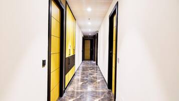 A hallway with a marble floor, yellow and black doors, and recessed lighting.