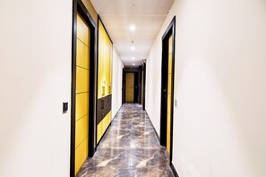 Un pasillo con piso de mármol, puertas negras y amarillas, e iluminación empotrada.