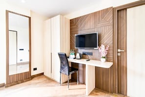 A modern room with a built-in desk, a flat-screen TV, a chair, and a mirror.