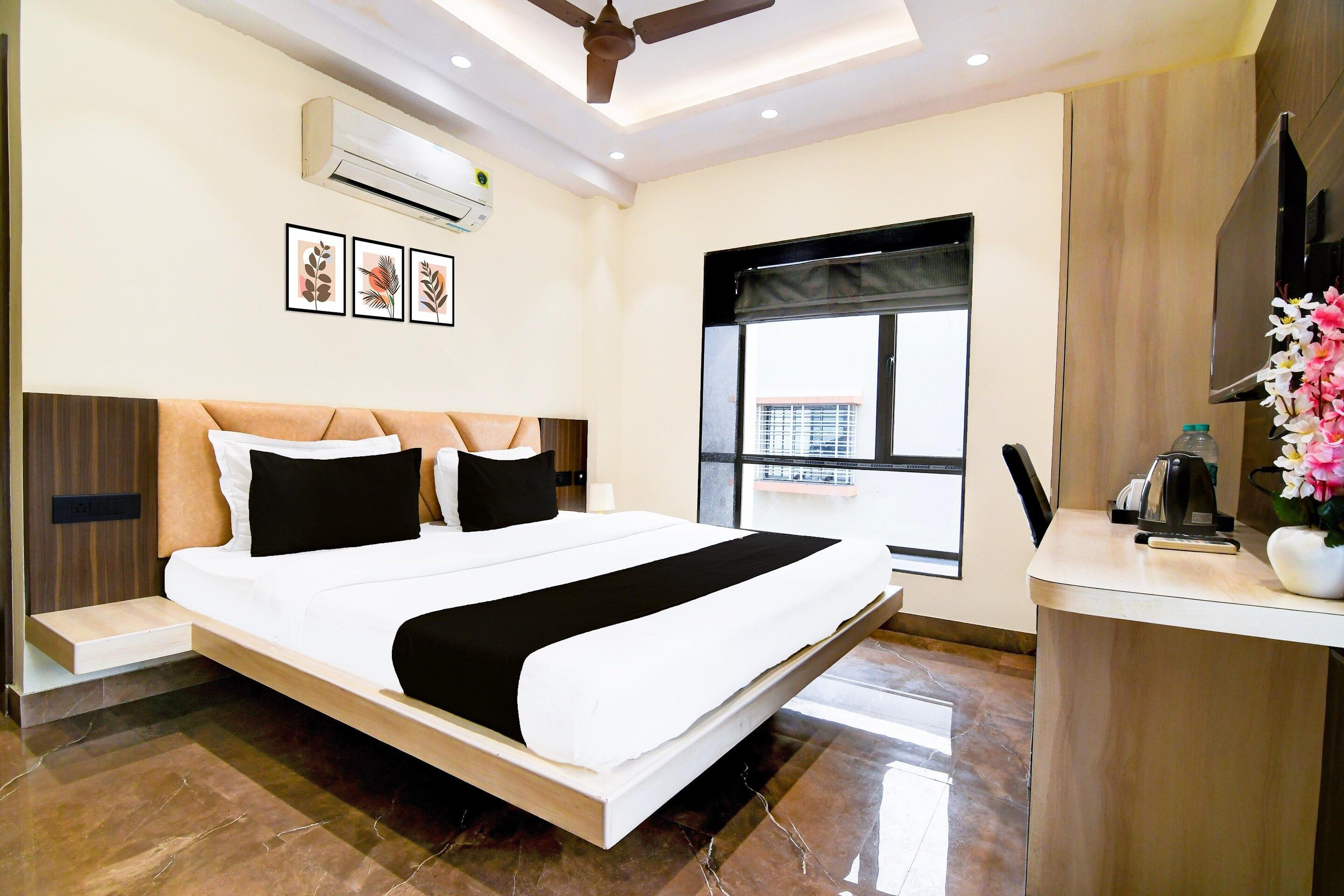 A modern hotel room with a bed, a desk, an air conditioner, and a window with a view.