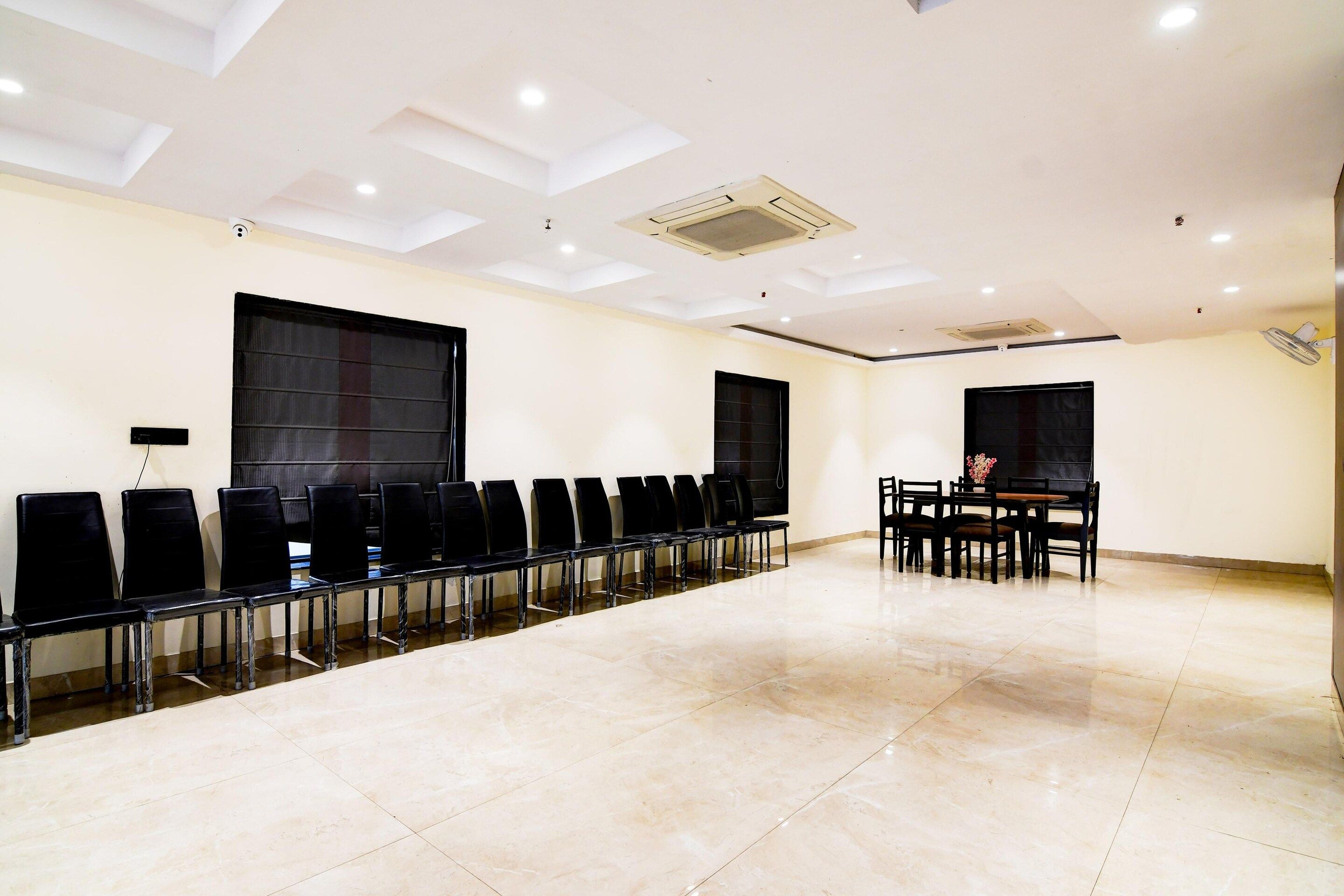 A conference room with rows of chairs, a table with chairs, and a large window.