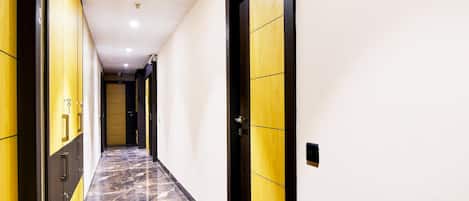 A hallway with lockers on the left and a door with a wooden panel on the right.