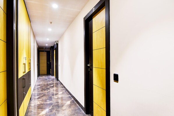 A hallway with lockers on the left and a door with a wooden panel on the right.