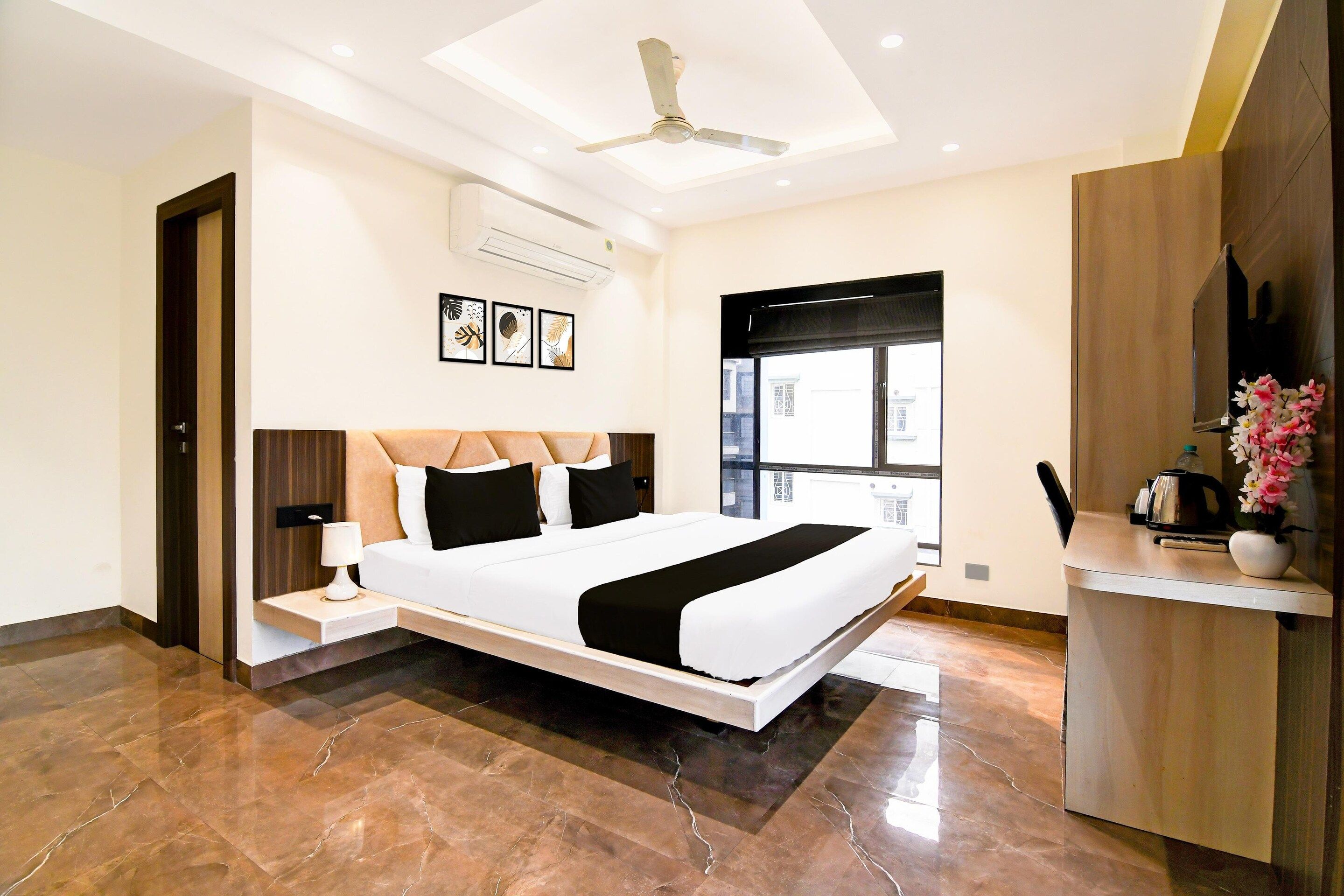A modern hotel room with a large bed, a desk, and a ceiling fan.
