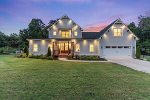 A two-story house with a front porch, a garage, and a well-maintained lawn. - Luxury Pool & Spa Villa + Golf Cart to Lake Dock (Gainesville)