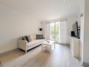 Een moderne woonkamer met een bank, salontafel en een tv op een dressoir.
