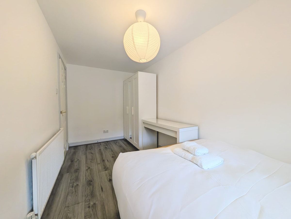 Une chambre à coucher comprenant un lit, une table de chevet, une armoire et un luminaire suspendu.