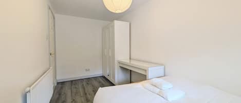 Un dormitorio con cama, mesita de noche, armario e iluminación colgante.