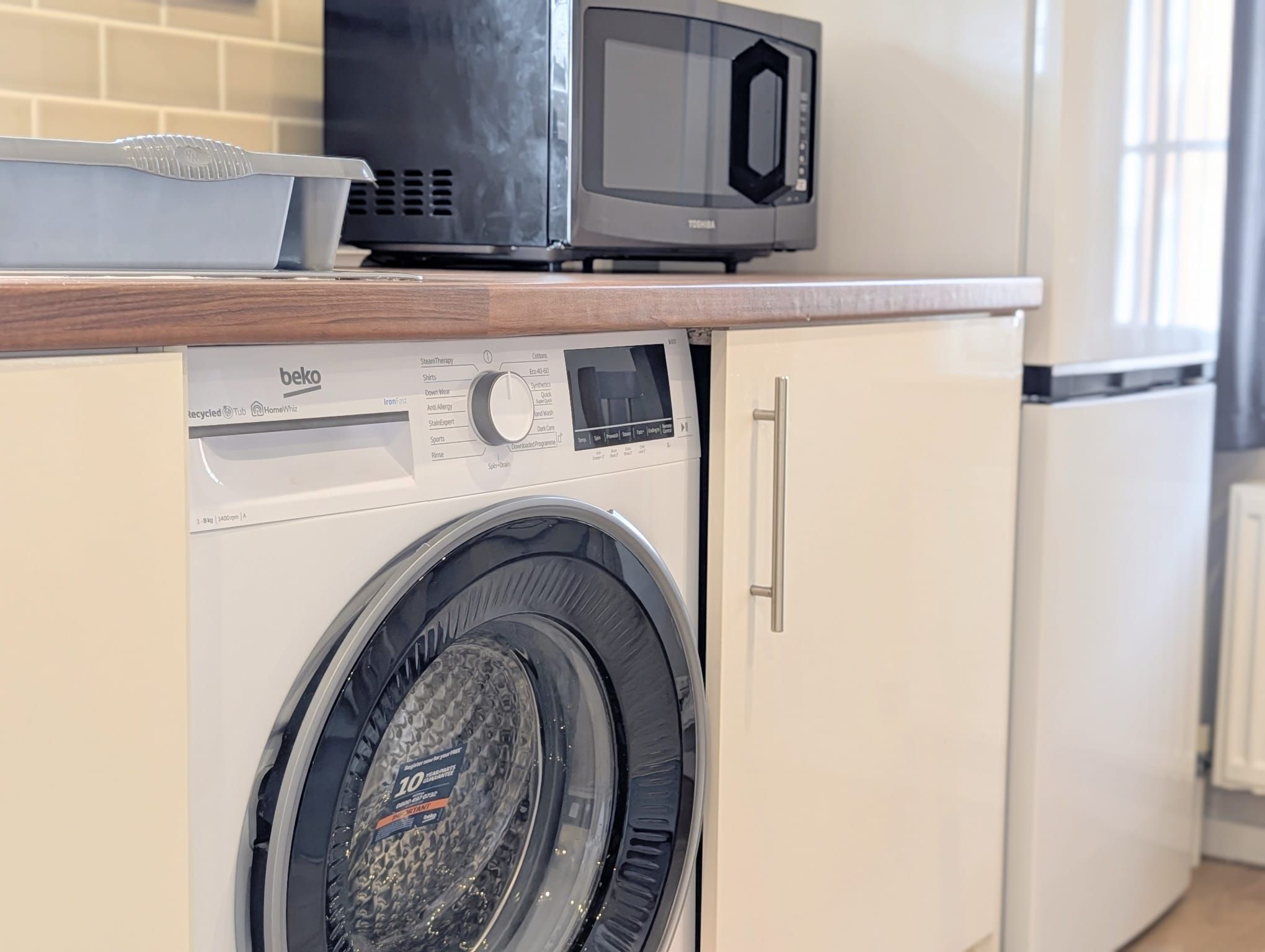 A washing machine with a control panel and a microwave above it.