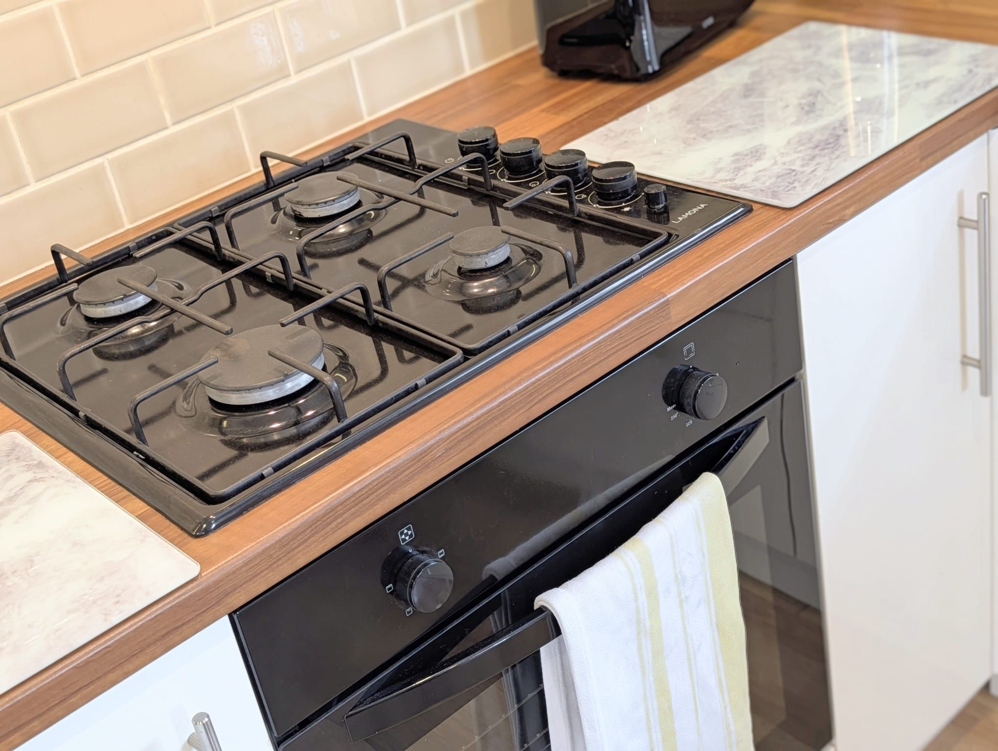 A kitchen with a four-burner stove, a black oven, and a wooden countertop.
