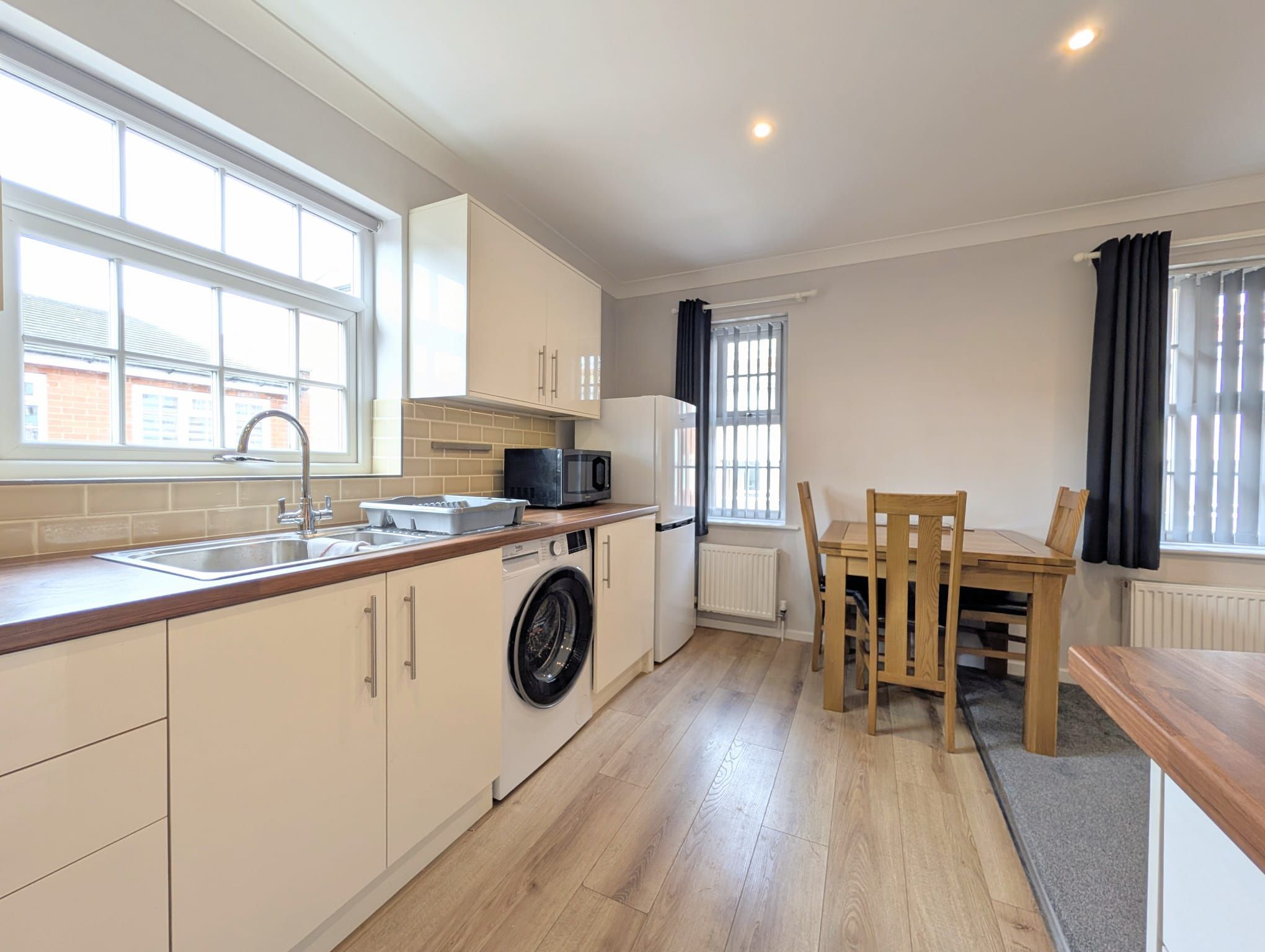 A compact kitchen with a washing machine, a microwave, and a dining area with a table and chairs.