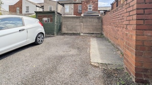 A residential area with a white car parked in a driveway, a brick wall, and a green gate. - Stylish Southport Town Centre Retreat + Parking (Southport)