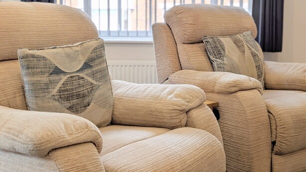 A sectional sofa with patterned cushions in a room with a window and blinds. - Stylish Southport Town Centre Retreat + Parking (Southport)