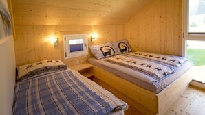 Habitación tipo cabaña con dos camas, una ventana con persianas e iluminación en la pared.
