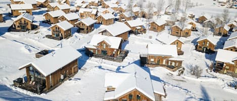 A cluster of wooden cabins with snow-covered roofs, set in a snowy landscape.