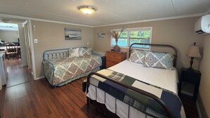 Un dormitorio con dos camas, un aparador, una ventana con vistas y una lámpara en el techo.