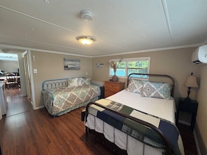 A bedroom with two beds, a dresser, a window with a view, and a ceiling light. - Lakefront 2-bedroom home on Palo Pinto Lake with Fishing Dock (Gordon)